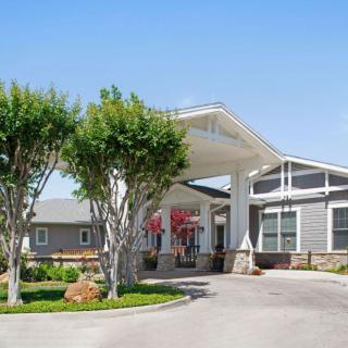 A modern residential building with a welcoming entrance surrounded by trees and landscaping.