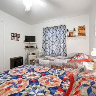 A cozy bedroom featuring colorful quilts and minimal decor with a small TV and shelves.