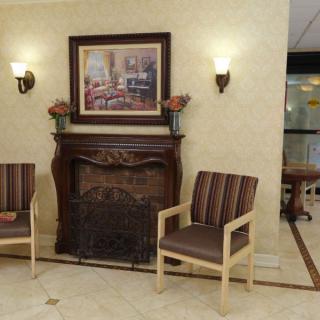 A cozy lobby area featuring a decorative fireplace, two chairs, and wall art.