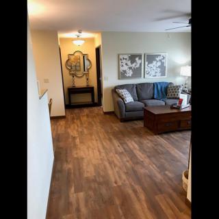 A cozy living room with a couch, coffee table, and wall artwork on wooden flooring.