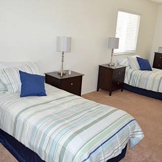 A bedroom with two neatly made twin beds and matching lamps on bedside tables.