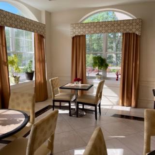 A bright and inviting dining area with natural light filtering through large windows, complemented by elegant curtains and tasteful furnishings.