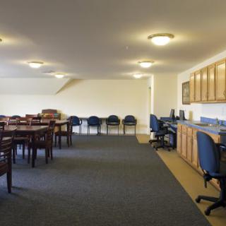 A spacious meeting room with tables and chairs arranged on a carpeted floor.