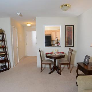 A cozy living space with a small dining area, featuring a table and chairs, bookshelf, and wall decor.