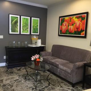 A cozy and modern living room featuring a comfortable sofa, decorative artwork, and a glass coffee table.