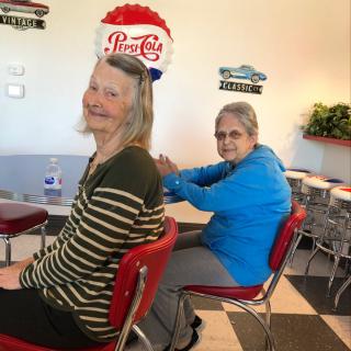 Two people in a vintage-themed diner, one wearing a retro style hat.