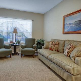 A cozy living room with a sofa, two armchairs, and a large window letting in natural light.