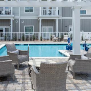 A modern apartment complex features an inviting swimming pool surrounded by cozy outdoor seating and patio furniture.
