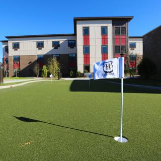 A modern building with a green lawn and a flag on a sunny day.
