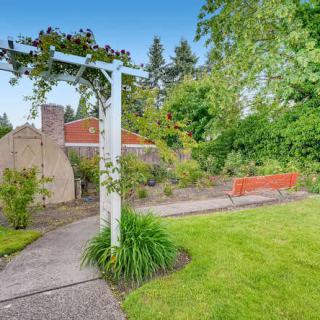 A peaceful garden setting with a pathway, bench, and lush greenery.