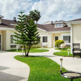A well-maintained residential courtyard with a pathway, lush grass, and outdoor seating.