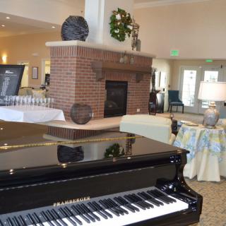 A cozy living room with a grand piano and brick fireplace.