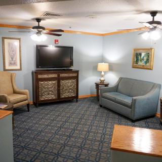 A cozy living room with a sofa, armchair, television, and decorative artwork on the walls.