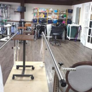 A well-equipped rehabilitation room featuring parallel bars and various therapy equipment.