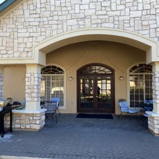 A building entrance with a stone facade, featuring an arched entryway and outdoor seating.