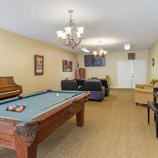 A cozy game room featuring a pool table, piano, and comfortable seating with a television.