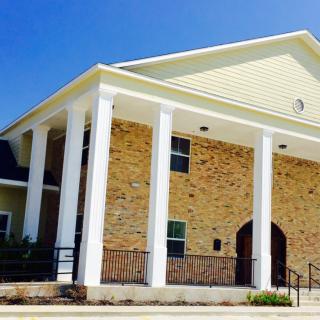 A brick building with white columns on a sunny day.