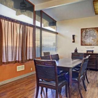 A modern dining room with a large table, chairs, and natural light streaming through the windows.