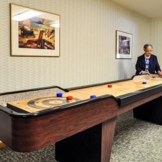 A person playing shuffleboard in a game room.