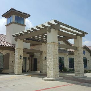 A modern architectural building featuring a welcoming entrance with a pergola and stone pillars.