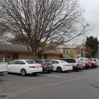 A row of parked cars in front of a building on an overcast day.