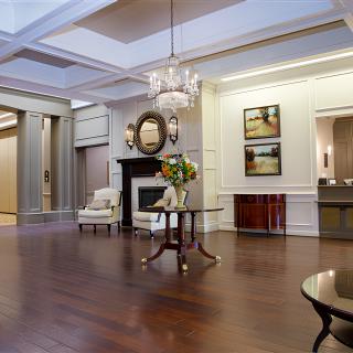An elegant lobby featuring a chandelier, fireplace, floral arrangement, and stylish furniture on a wood floor.