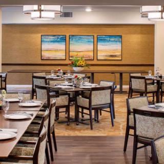A well-decorated dining area with neatly arranged tables and chairs, featuring modern artwork on the walls.