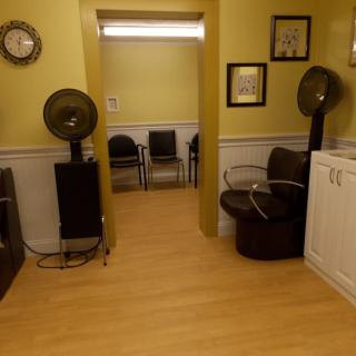 Interior view of a salon waiting area with hair dryers and seating.