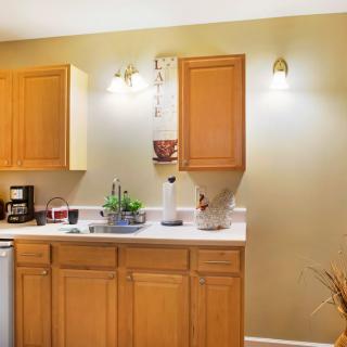 A cozy kitchen corner with wooden cabinets, a coffee maker, and ambient lighting.