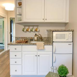 A compact kitchen space with white cabinets, a granite countertop, and essential appliances.