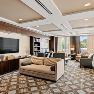 A modern living room with elegant furnishings, featuring a comfortable sofa, large television, and bookshelves.