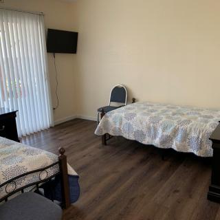 A bedroom with two single beds, a chair, and a wall-mounted television.