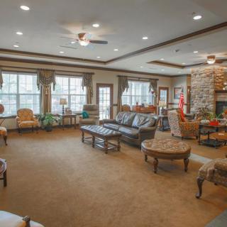 A spacious and elegantly designed living room featuring comfortable seating, a stone fireplace, and large windows with drapes.