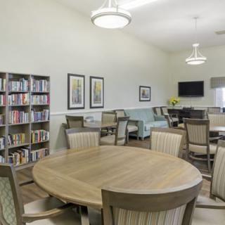 A modern library reading room with bookshelves, tables, and chairs.
