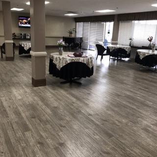 A spacious dining area with round tables and wooden flooring.
