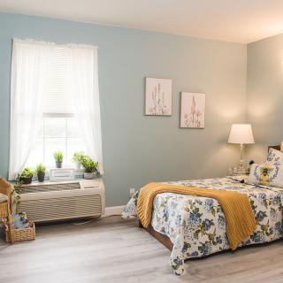 A cozy bedroom with blue walls, a floral bedspread, and soft lighting.