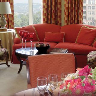 A cozy living room with a red sofa, a coffee table, and floral decor.