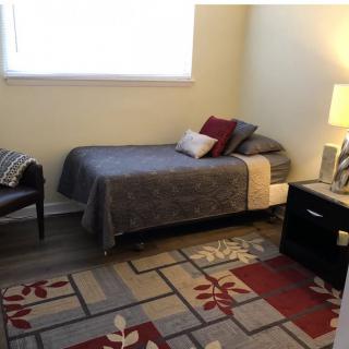 A cozy bedroom with a single bed, nightstand, and decorative rug.