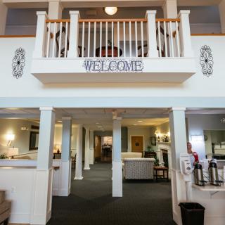 A welcoming lobby interior with pillars and a 'Welcome' sign on a two-story structure.