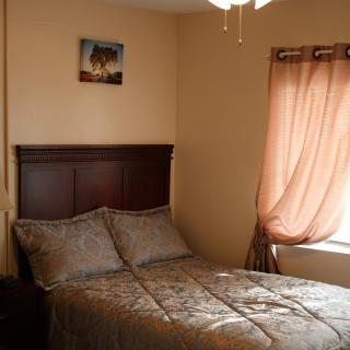 Cozy bedroom with a bed, decorative pillows, and a window with curtains.