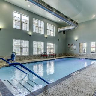 A modern indoor swimming pool with large windows and ceiling lights.
