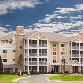 A modern multi-story residential building with balconies set against a partly cloudy sky.