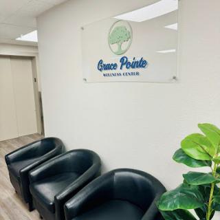 A modern waiting area featuring black chairs and a sign for 'Green Pointe' along with indoor plants.