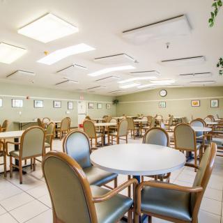 A spacious and well-lit empty dining room with multiple tables and chairs.
