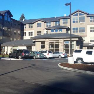 A multi-story residential building with a parking lot full of cars on a clear day.