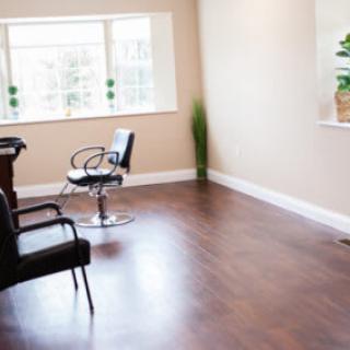 A minimalist salon interior with chairs and a wooden floor.