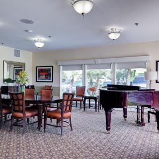 A well-furnished lounge with dining tables, chairs, and a piano.