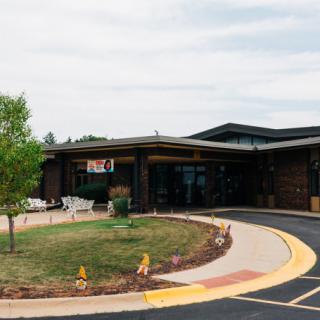 A modern building with a landscaped entrance and curved driveway.