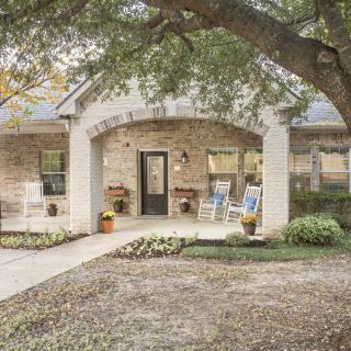 A charming brick house with a cozy front porch and surrounding greenery.