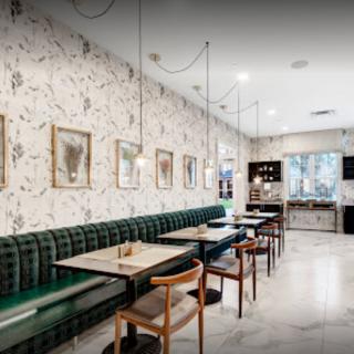 A modern restaurant interior featuring green upholstered seating, stylish lighting fixtures, and wall art.